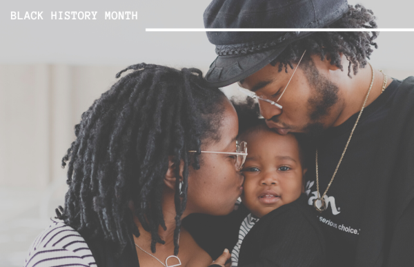 Buckner family A Black mother and father kiss a young baby.