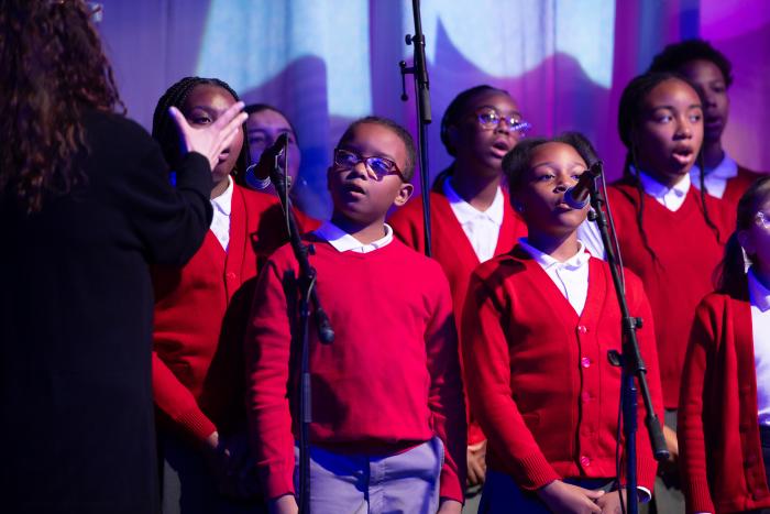 A small group of young children sing.