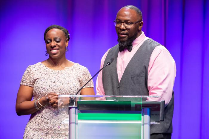 Two people, a man and woman, stand at a podium