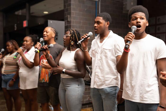 A group of young people with microphones sing.