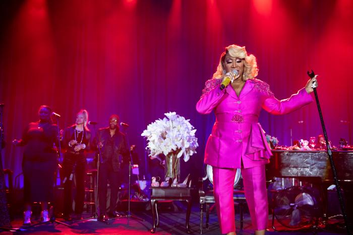 Woman stands holding microphone and microphone stand.